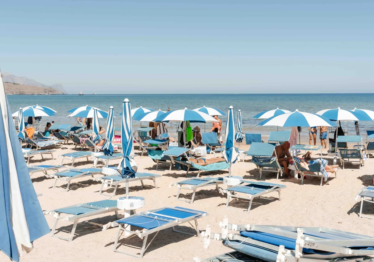 Blue umbrellas and loungers lined up at a beach club on the gulf